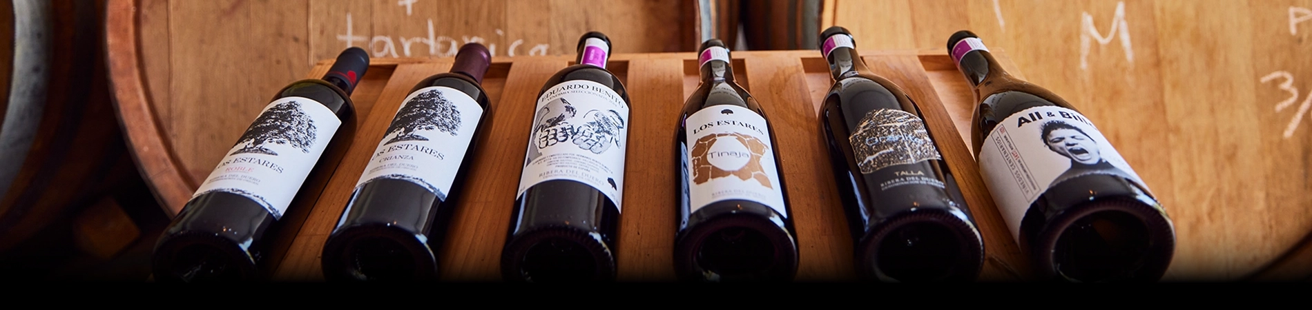 Botellas de la Bodega Pago de los Estares con fondo de barricas